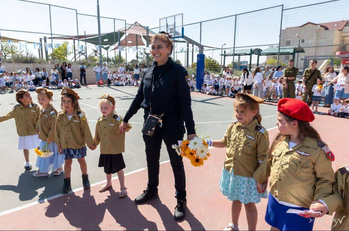 1. Children in scout uniforms holding flowers during outdoor event at Efrat Development Foundation.