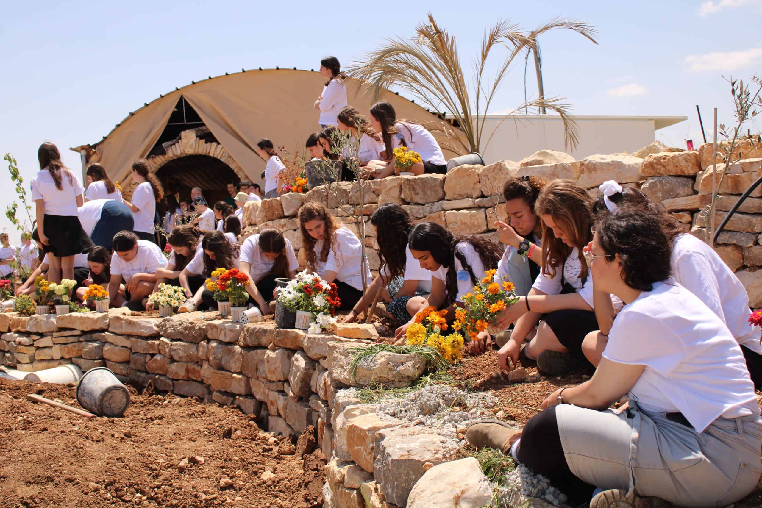 Young girls planting flowers at Efrat Development Foundation community event.
