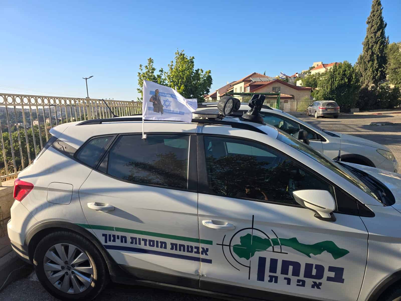 Flag on car with Israel emblem and security symbols, representing Efrat Development Foundation's safety programs.