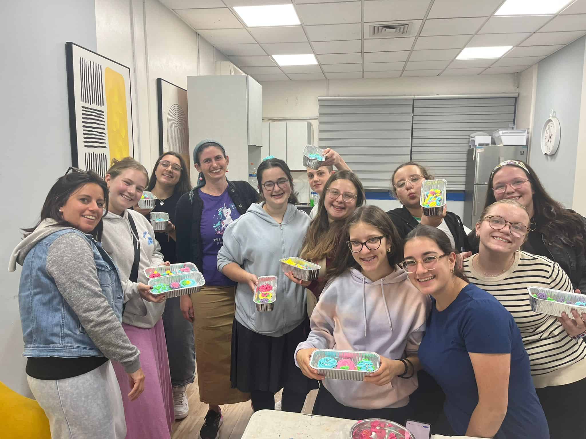 Women and girls participating in a community activity organized by Efrat Development Foundation, holding colorful craft projects.